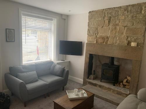 ein Wohnzimmer mit einem Sofa und einem Kamin in der Unterkunft Tipsy Cottage Charming 2 bedroom home. in Burley in Wharfedale