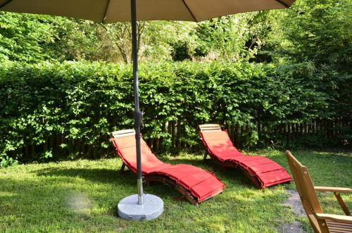 three red chairs under an umbrella in the grass at Wohnidylle auf schönem Anwesen im Wald in Bad Honnef am Rhein
