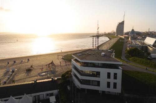 Blick auf den Strand, ein Gebäude und das Meer in der Unterkunft Bheaven I Penthouse Premium Apartment in Bremerhaven