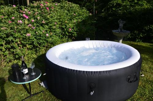 a large hot tub in a yard with a bottle of wine at Wohnidylle auf schönem Anwesen im Wald in Bad Honnef am Rhein