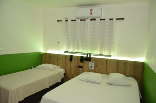 two beds in a room with green and white at HOTEL VITORIA REGIA in Engenheiro Beltrão