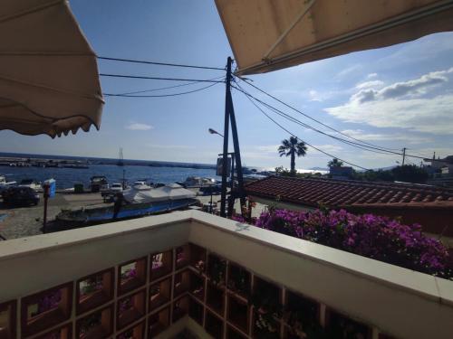 a view of the ocean from a balcony with purple flowers at Peristerianos apartments in Nea Skioni