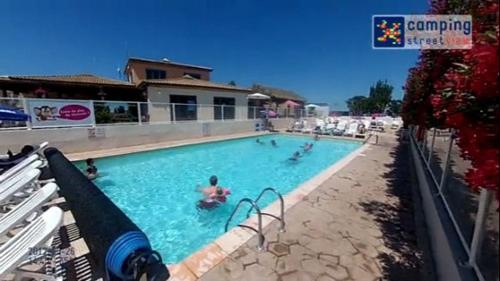 a swimming pool with people in the water at Mobil home 6/8personnes in Sérignan