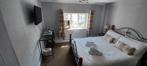 a bedroom with a bed with white sheets and a window at Winchester Arms in Trull