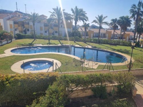 ein Pool in einem Park mit Palmen und Gebäuden in der Unterkunft SALINAS DE VERA APARTAMENTO in Vera