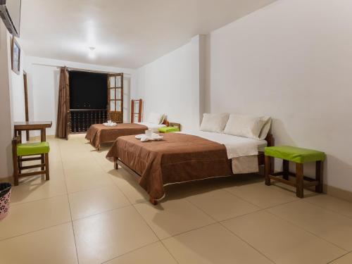 a bedroom with two beds and a table and a window at Hostal La Morada in Chachapoyas