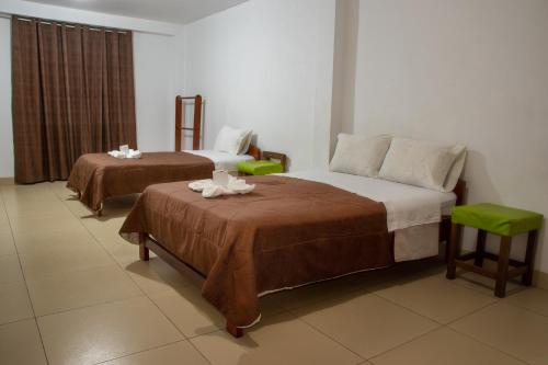 a hotel room with two beds and two tables at Hostal La Morada in Chachapoyas