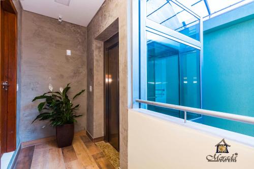 a hallway with a window and a potted plant at Hotel Morada Del Este in Canoas
