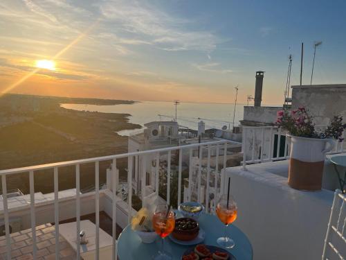 a balcony with two glasses of wine and a view of the ocean at Trame - La Naca sul Porto in Polignano a Mare