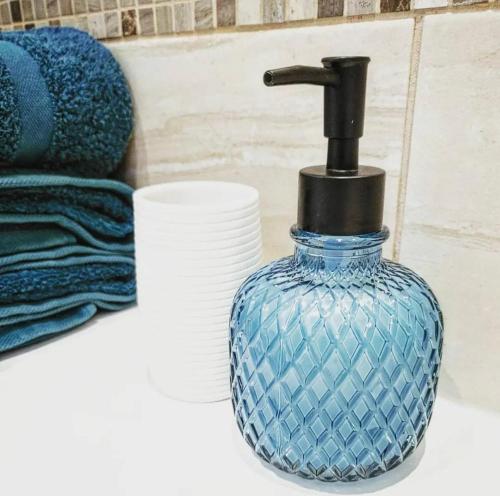 a blue glass bottle sitting on a bathroom counter at The Wee Stay - Rural Guest Suite with Woodfired Hot Tub and outside Kitchen and covered Livingroom area in Crook of Devon