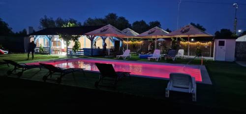 a swimming pool with chairs and umbrellas at night at Splendoarea Deltei in Maliuc