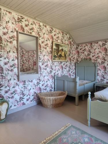 a bedroom with pink floral wallpaper and a mirror at Gamla Kooperativa in Ekshärad