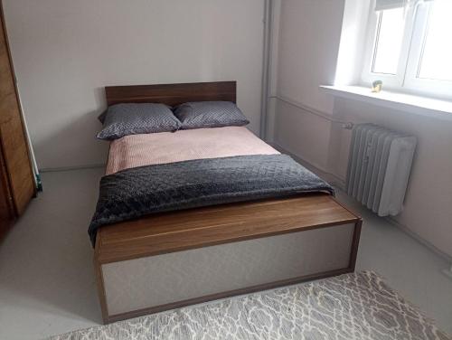 sypialnia z łóżkiem z drewnianą ramą i oknem w obiekcie Kwatera prywatna w centrum w Świnoujściu