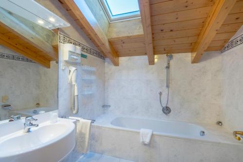 La salle de bains est pourvue d'une baignoire et d'un lavabo. dans l'établissement Hotel Ciamp, à Santa Cristina Valgardena