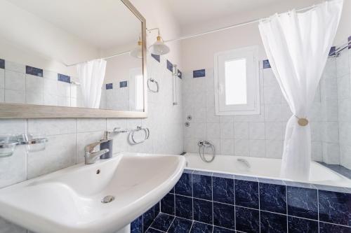 a white bathroom with a sink and a tub at Drita Studios & Apartments in Svoronata