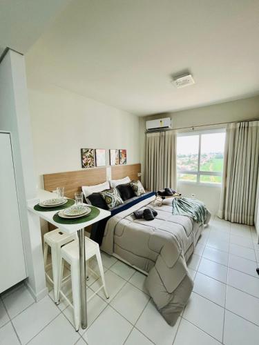 a bedroom with a bed and a table in it at Flat 912 Super Aconchegante! in Ribeirão Preto