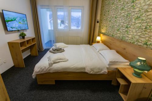 a bedroom with a large bed and a television at Casa Liana in Buşteni