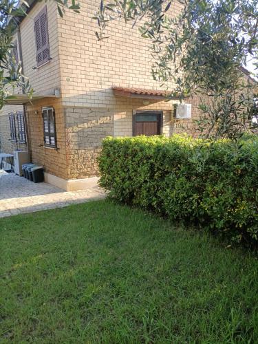 a house with a hedge in front of a building at VILLA GIULIANA stanze con bagno interno in Villa a 350 mt spiaggia libera Lido delle Sirene in Anzio