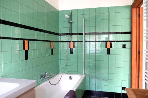 baño de azulejos verdes con bañera y lavamanos en Villa Bérylune, en Ostende