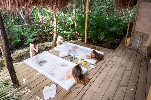 two girls laying in a hot tub on a deck at Serenity Authentic Glamping Tulum in Xpu Ha