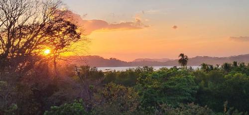 a sunset over a field with trees and a body of water at La Puesta del Sol B&B in Carrillo