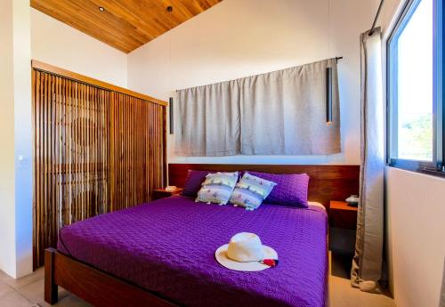 una camera con un letto viola e un cappello sopra di La Joya de Nosara a Playa Pelada