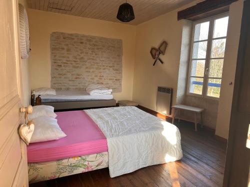 a bedroom with two beds and a brick wall at L'ILEAU in La Taillée