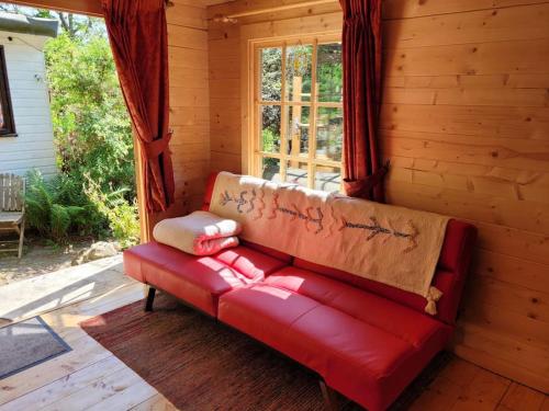 a red couch sitting in a room with a window at Tan y coed's Rosemary Cabin in Conwy
