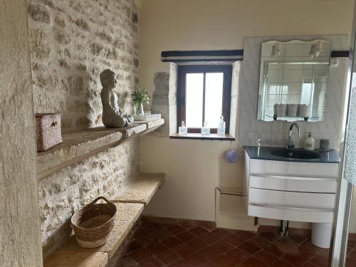 a bathroom with a sink and a statue on the wall at L'ILEAU in La Taillée