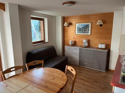 ein Wohnzimmer mit einem schwarzen Sofa und einem Tisch in der Unterkunft Chamrousse Appart 8 personnes au pied des pistes in Chamrousse