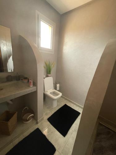 a bathroom with a toilet and a sink and a window at Peaceful Pool Villa in Marrakech