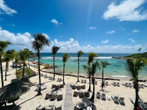 ein Strand mit Liegestühlen, Palmen und dem Meer in der Unterkunft Bluewave in Saint-François