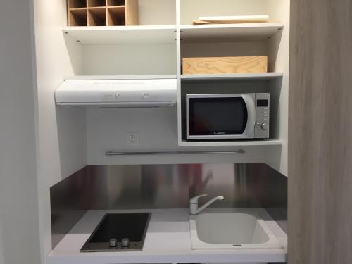 uma cozinha com forno de micro-ondas e pia em Bluewave em Saint-François