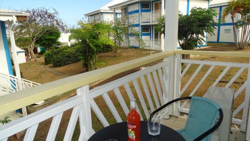 Ein Tisch und ein Stuhl auf einem Balkon mit Blick auf ein Haus in der Unterkunft Bluewave in Saint-François