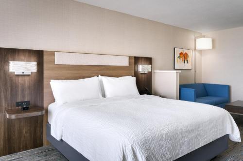 a bedroom with a large white bed and a blue chair at Holiday Inn Express and Suites Helena by IHG in Helena