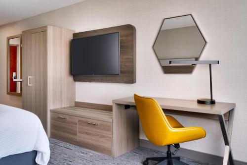 a bedroom with a desk and a tv and a yellow chair at Holiday Inn Express and Suites Helena by IHG in Helena