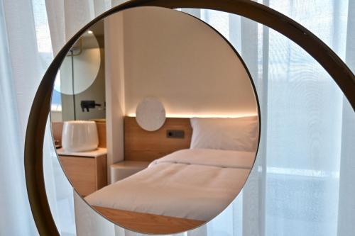 a round mirror in a bedroom with a bed at Balance Accommodation in Stavros