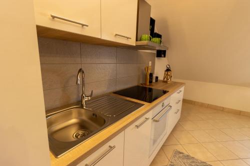 a kitchen with a stainless steel sink and white cabinets at STYLISH STUDIO APARTMENT BURE in Murter