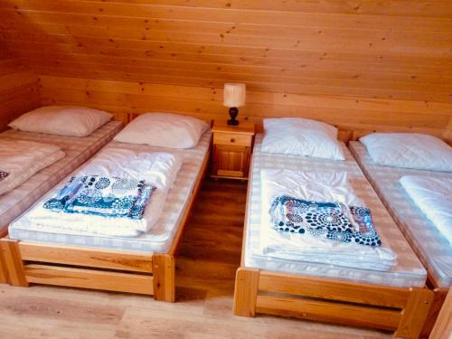 two twin beds in a room with wooden walls at Domki na Tynioku in Koniaków