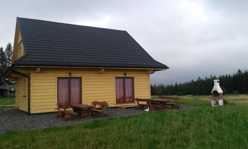 a small yellow building with picnic tables and benches at Domki na Tynioku in Koniaków