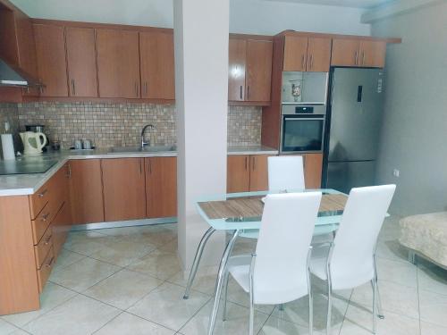 a kitchen with a dining table and white chairs at Sia's house near to airport in Artemida