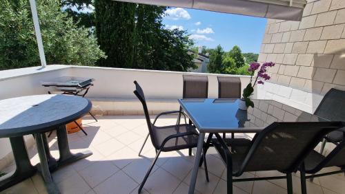 un patio con 2 mesas y sillas en un balcón en Apartman Bela en Njivice