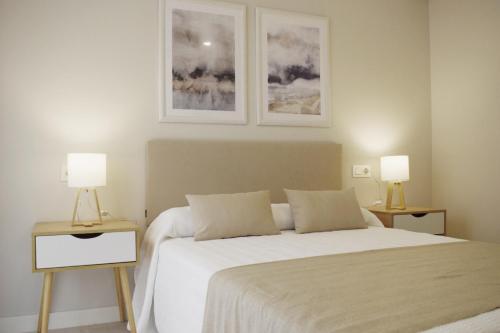 拉科魯尼亞的住宿－JOMAR Apartamento en Coruña，一间卧室配有一张白色床和两盏灯。