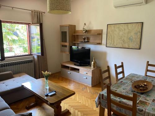 a living room with a table and a tv at Apartmani Ana Borovac in Funtana