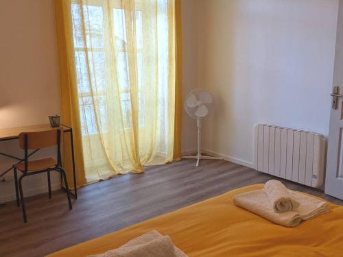 - une chambre avec un lit, un bureau et une fenêtre dans l'établissement À l'ombre de l'abbatiale, 90 m² rénovés 3 chambres, à Aurillac