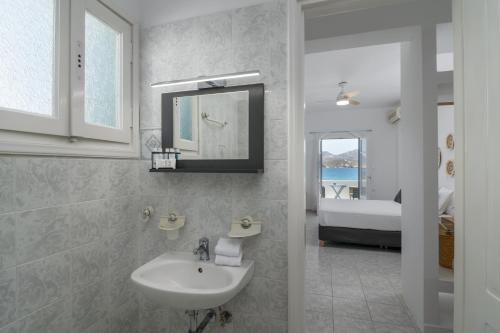 baño con lavabo, espejo y cama en ILIAS SEA VIEW, en Pollonia