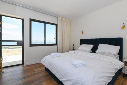 a bedroom with a large white bed with a large window at נוף העמק - דירה מהממת עם נוף עוצר נשימה in Nof Kinneret