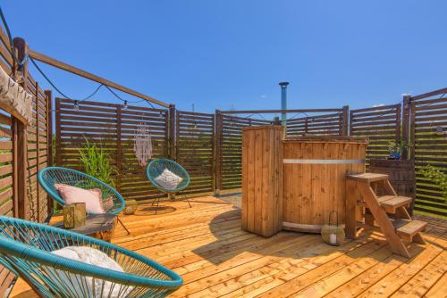 a wooden deck with chairs and a hot tub at Domki Mazurska Dolina in Mikołajki