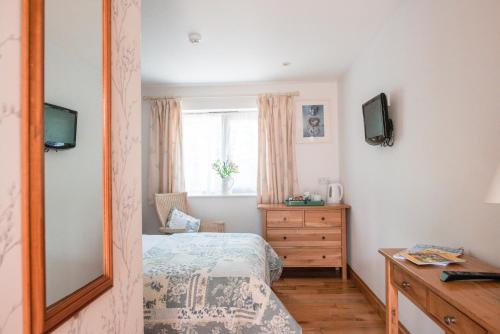 1 dormitorio con cama, tocador y espejo en The Talbot Arms, en Lyme Regis