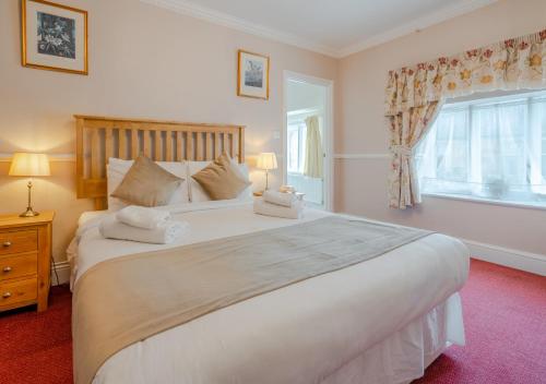 a bedroom with a large white bed and a window at Crown Hotel Cotswold in Blockley